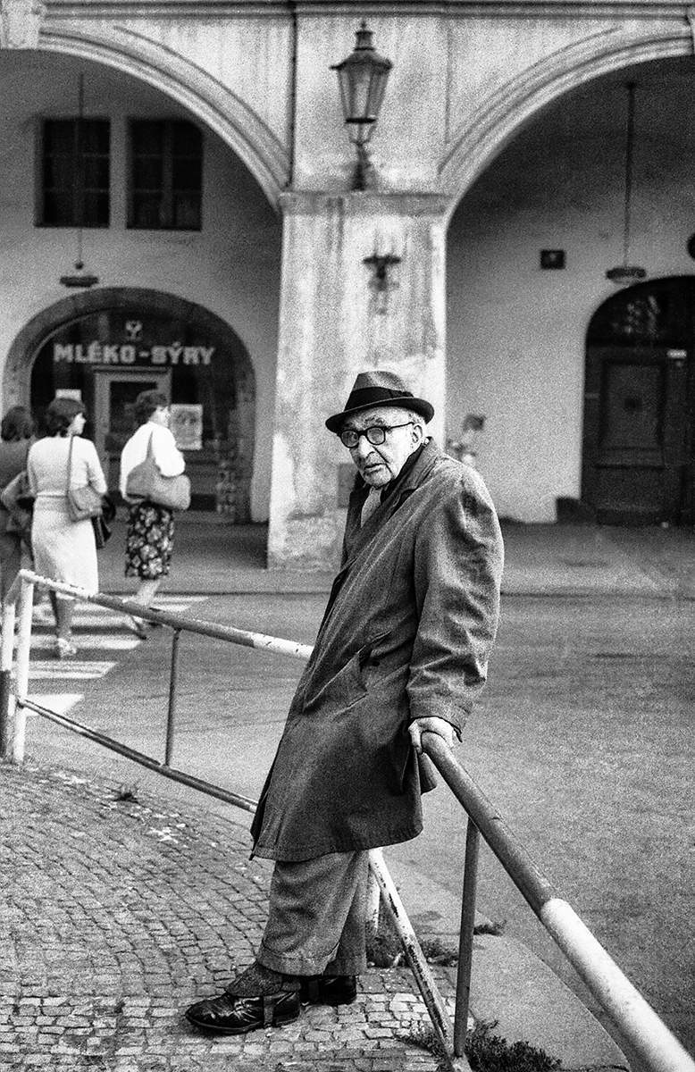 Opíral se o zábradlí na Malostranském náměstí, šedivém normalizační dobou. Praha, 1986.