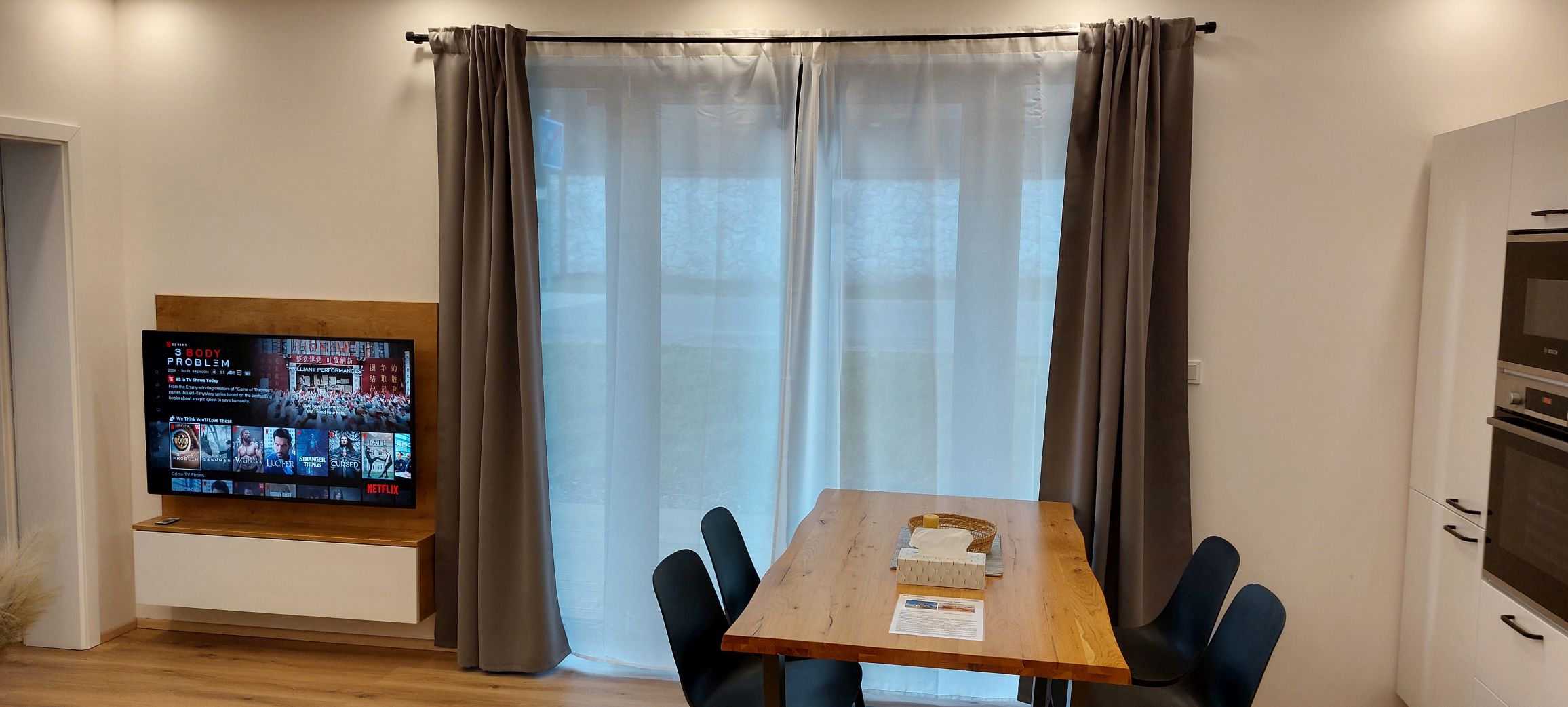 Jídelní stůl z masivu, přímo před francouzským oknem, záclony poskytují perfektní soukromí.